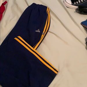 Navy blue adidas track pants with orange stripes